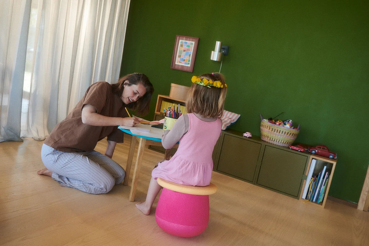 Dziewczynka rysuje przy stoliku, siedząc na siedzisku Stapelstein Dynamic small flowers