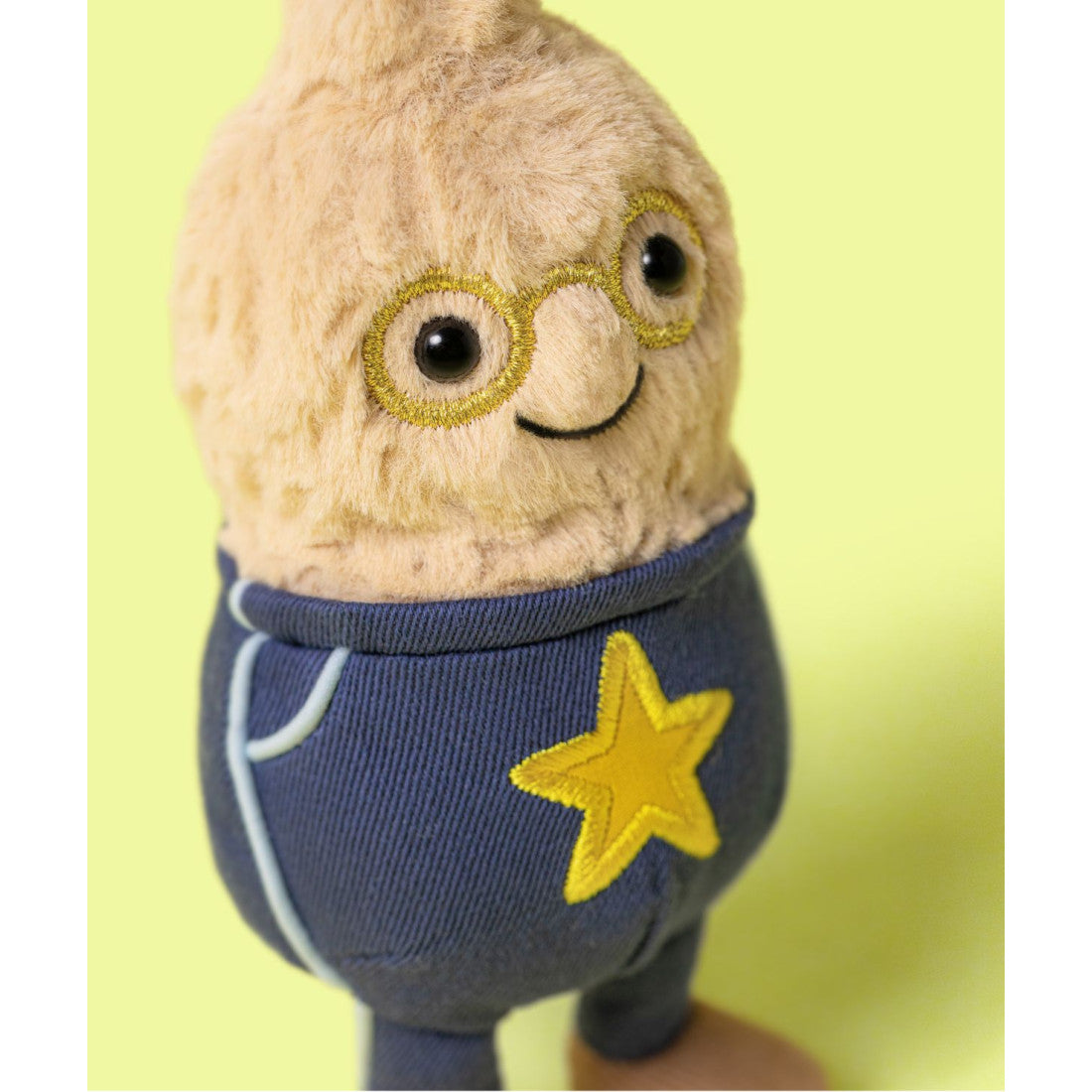 Zbliżenie na wyhaftowane okulary i uśmiech fistaszka Jellycat