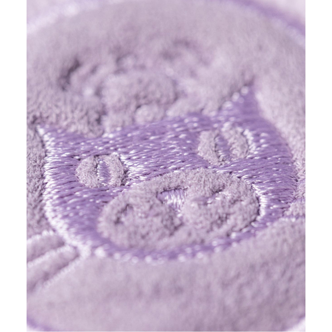 Maskotka Jellycat Amuseables – Makaronik Liliowy May 12 cm, zbliżenie na wyhaftowane logo Jellycat