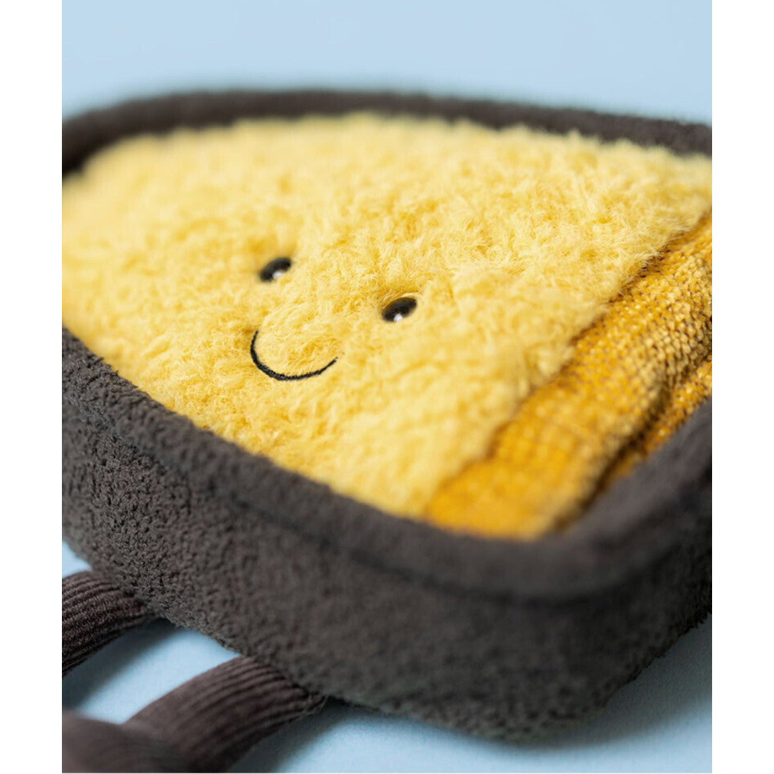 Maskotka Jellycat Amuseables – Ser Raclette 21 cm, zbliżenie na buzię, zdjęcie na błękitnym tle