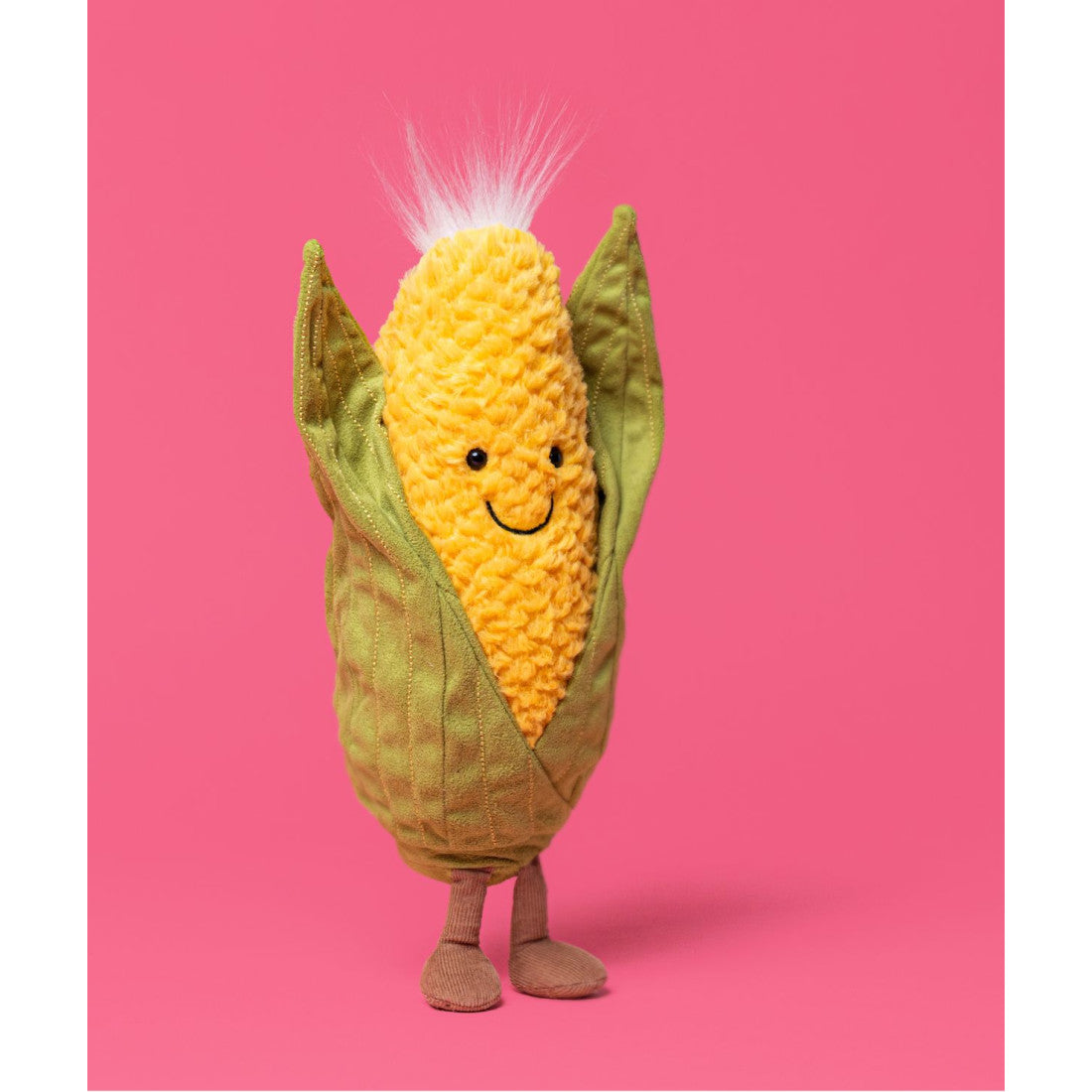 Maskotka Jellycat Amuseables – Kolba Kukurydzy 27 cm, na nóżkach, zdjęcie na różowym tle